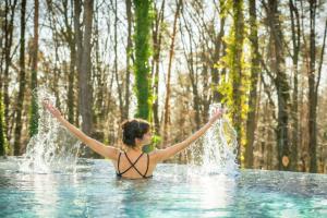 Una mujer está de pie en el agua con los brazos en alto. en RETTER Bio-Natur-Resort, en Pöllauberg