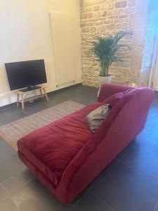 um sofá vermelho numa sala de estar com uma televisão em Loft de charme avec terrasse et jardin au Fort d’Asfeld em Sedan
