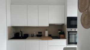 una cucina bianca con armadietti bianchi ed elettrodomestici neri di Playa y Comodidad en Benicàssim a Benicàssim