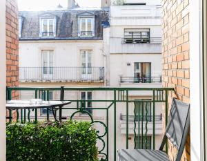 un balcone con tavolo, sedie e edifici di Résidence Courcelle a Levallois-Perret