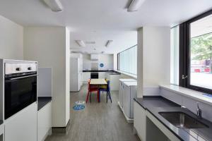 a kitchen with white counters and a table and a window at Frances Gardner in London