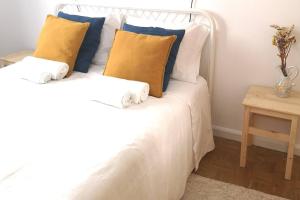 a white bed with blue and yellow pillows on it at The Green Gate Patio House in Nazaré