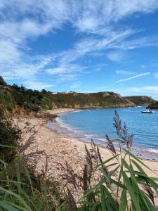 einen Sandstrand mit einem Boot im Wasser in der Unterkunft Portelet Bay in St Brelade