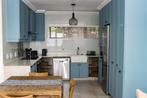cocina con armarios azules y mesa de madera en No1 Wenonah Trafalgar en Southbroom