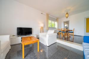 ein Wohnzimmer mit einer Couch, einem Fernseher und einem Tisch in der Unterkunft HomeHolidaysRentals Himalaia - Costa Barcelona in Santa Susanna