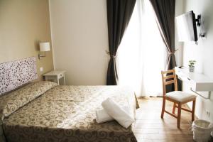a bedroom with a bed and a desk and a window at B&B Vivere San Vito Lo Capo in San Vito lo Capo