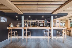 a bar with stools and tables in a room at L'Auberge Nordique in Le Grand-Bornand