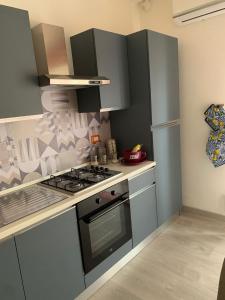 泰爾米尼伊梅雷塞的住宿－Albachiara Termini，厨房配有灰色橱柜和炉灶烤箱