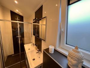 een badkamer met een wastafel en een glazen douche bij Exclusieve vakantievilla ***** Markermeer in Bovenkarspel