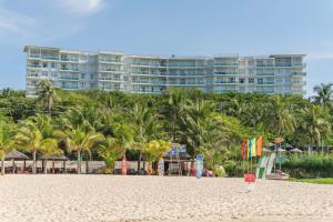 a beach with palm trees and a large building at OCEAN VISTA in Phan Thiet