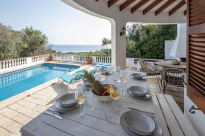 una mesa de comedor con copas de vino y una piña en el patio en Villa MAESO, en Son Bou