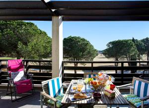 a table with food and drinks on a patio at VERT PARADIS - Vue apaisante sur GOLF, Pins Parasols, 2è étage - 80 m2 dont Terrasse avec Pergola, 2 chambres, 3ét iles, 3 CLIM, WIFI - Piscine, Parking et Park à vélos, Ascenseur - en Option Linge, Ménage - Pistes cyclables, Mer à proximité in Saint-Cyprien
