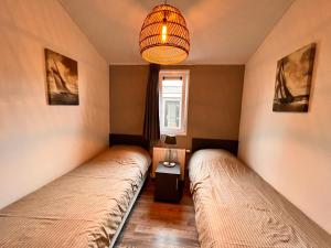 two beds in a room with a chandelier at Exclusieve vakantievilla ***** Markermeer in Bovenkarspel