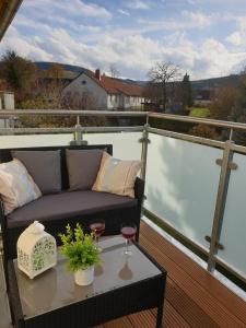 a balcony with a couch and two glasses of wine at Ferienwohnung Laura in Langelsheim