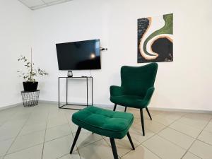 un soggiorno con 2 sedie verdi e una TV di Apartment Central 10D 55qm Wi-Fi free Parking calm back house a Dortmund