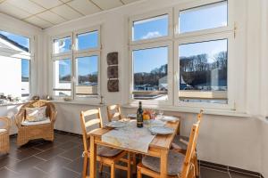 une salle à manger avec une table, des chaises et des fenêtres dans l'établissement Villa-Seiler-in-Binz-3-Raum-Ferienwohnung-Nr-5-Toplage-wenige-Schritte-zum-Strand, à Binz