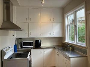 a kitchen with white cabinets and a sink and a microwave at Wellington double bedroom in Wellington