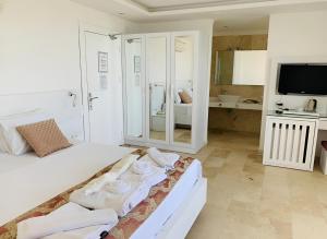 a white bedroom with a bed with towels on it at Oasis Hotel in Kalkan