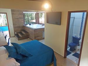 a bedroom with a bed and a tub and a television at Pousada Aquarela - Macacos in Macacos