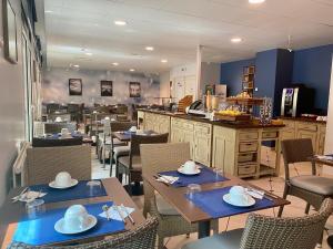 a dining room with tables and chairs and a kitchen at La Closerie SPA & Résidence Hôtel in Deauville