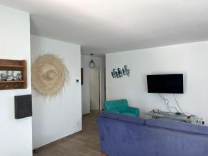 sala de estar con sofá azul y TV en Tierra Del Viento - Villa Proche de la Mer, en Peyriac-de-Mer