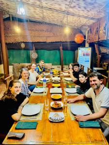 a group of people sitting around a long wooden table at Pearl White House in Udawalawe