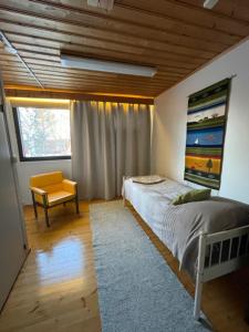 a bedroom with a bed and a chair and a window at Tiitun Tupa Ivalo in Ivalo