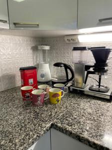 a kitchen counter with cups and a coffee maker at Tiitun Tupa Ivalo in Ivalo