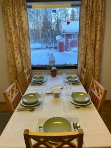 Una mesa de comedor con platos y vasos y una ventana. en Tiitun Tupa Ivalo, en Ivalo