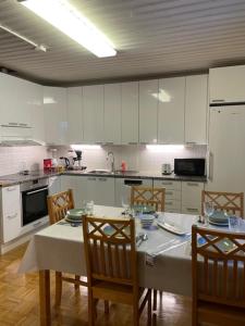 a kitchen with a table and chairs and a kitchen with white cabinets at Tiitun Tupa Ivalo in Ivalo