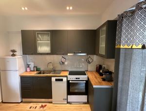 a kitchen with black cabinets and white appliances at Chic Apartment in Nature, 5-min walk to the Beach in Kalamata