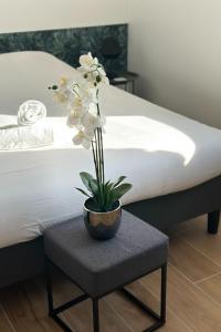 a potted plant on a table next to a bed at La Love Room de St Nazaire les Eymes in Biviers