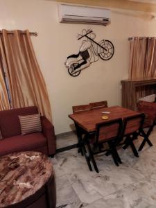 uma sala de estar com uma mesa e uma mulher numa bicicleta na parede em Lemon Tree Garden Villa em Pune