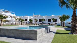 a swimming pool in front of a house with palm trees at Apartament Porto Marina in Torre de la Horadada