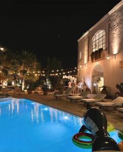 una piscina di fronte a un edificio di notte di Casina Colosso - relais&more - a Nardò