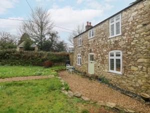 an old stone house with a chair in front of it at Norden Cottage in Weymouth