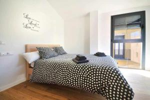 Un dormitorio con una cama con sábanas de lunares y una ventana. en Stunning apartment w amazing views and aircon, en Girona