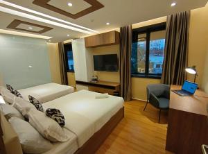 a bedroom with two beds and a desk and a laptop at MS Hotel Kuala Lumpur in Kuala Lumpur