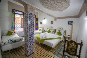a bedroom with three beds and a window at Riad Dar Rabha in Fez