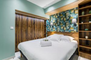 a bedroom with a white bed with a wooden wall at Hamac Suites - Suite du Parc 3 in Villeurbanne