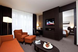 ein Hotelzimmer mit einem Sofa und einem Zimmer mit einem Bett in der Unterkunft Atlantic Hotel Lübeck in Lübeck
