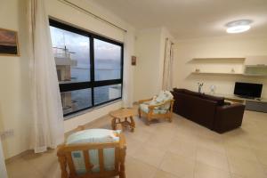 a living room with a couch and a large window at The Sea just Across the Road - Flat 3 in St. Paul's Bay