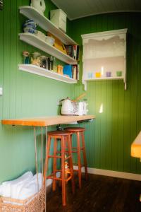 a green kitchen with a counter and stools at Gooseberry Shepherds Hut in Worcester