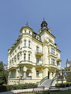 um grande edifício amarelo com escadas em frente em Hotel Mignon em Karlovy Vary