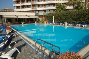 a large swimming pool with chairs and a building at Hotel Nettuno in Catania