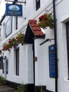 a sign on the side of a building with flowers at The Ship Inn in Holy Island