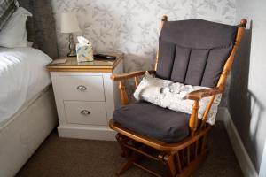 uma cadeira de balanço de madeira ao lado de uma cama em The Ship Inn em Holy Island