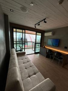 a living room with a large couch and a television at Luxuoso Studio particular reformado no Grand Mercure in Brasília