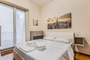 a white bedroom with a large window and a bed at Milano Via Del Fusaro 4 PAX Wi-Fi in Milan