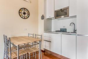 a kitchen with white cabinets and a table and a clock at Milano Via Del Fusaro 4 PAX Wi-Fi in Milan